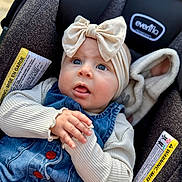 Sutton is registered to the contest to win money with this photo: baby, child, car_seat, denim, headband, bow, blue_eyes, cute, infant, clothing, sitting, hand, portrait, face, expression, soft_lighting, apparel, seat, warning_label, closeup