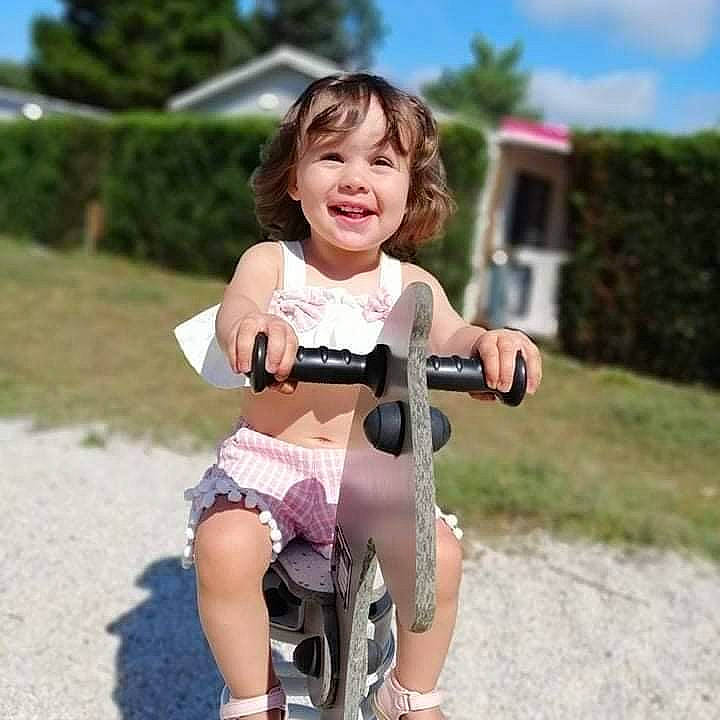 Alice participe au concours pour gagner de l'argent avec cette photo : bicycle_handlebar, bicycle_wheel, bicycles_equipment_and_supplies, dress, eye, face, footwear, grass, happy, head, joy, leisure, person, riding_toy, shorts, sky, smile, tire, toddler, toy