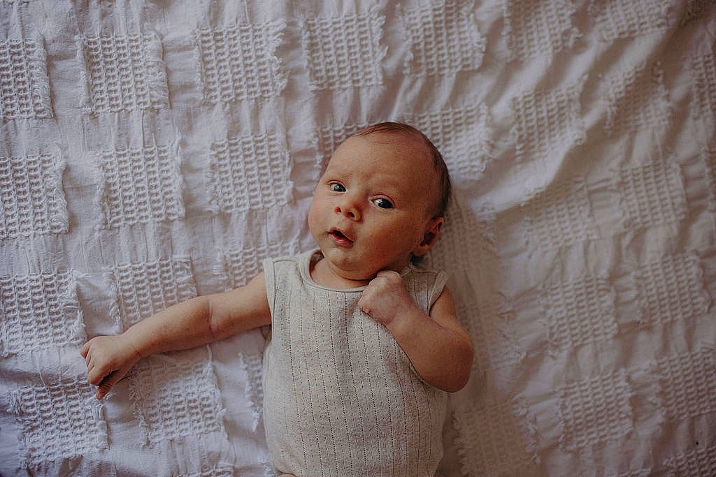Elliot is registered to the contest to win money with this photo: baby, baby_toddler_clothing, bedding, child, comfort, embellishment, flash_photography, floor, flooring, happy, linens, pattern, person, room, sitting, skin, sleeve, textile, toddler, wood