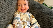 Remington is registered to the contest to win money with this photo: baby, babylaughing, blanket, clothing, couch, cushion, face, footwear, furniture, happy, head, homedecor, pajamas, person, photography, portrait, quilt, shoe, sitting, smile