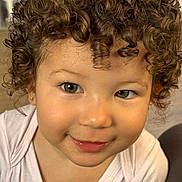Loni a rejoint le concours — aidez-le/la à gagner de superbes lots ! toddler, child, curly_hair, smiling, face, portrait, indoors, cute, young_child, person, skin, eyes, clothing, white_shirt, happy, baby, earring, close_up, head, expression