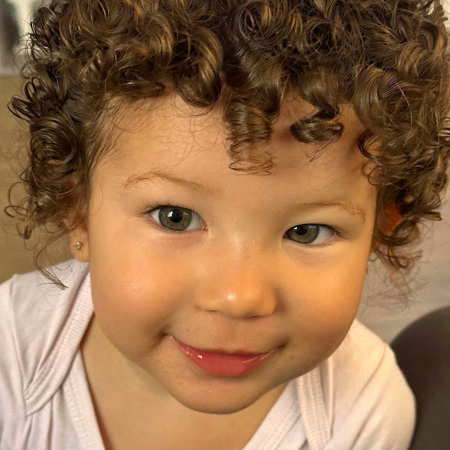 Loni a rejoint le concours — aidez-le/la à gagner de superbes lots ! baby, child, close_up, clothing, curly_hair, cute, earring, expression, eyes, face, happy, head, indoors, person, portrait, skin, smiling, toddler, white_shirt, young_child