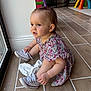 toddler, child, baby, dress, sneakers, floor, window, indoor, toy, play_area, hair_clip, person, footwear, converse, sitting, curious, light, natural_light, home, tile_floor