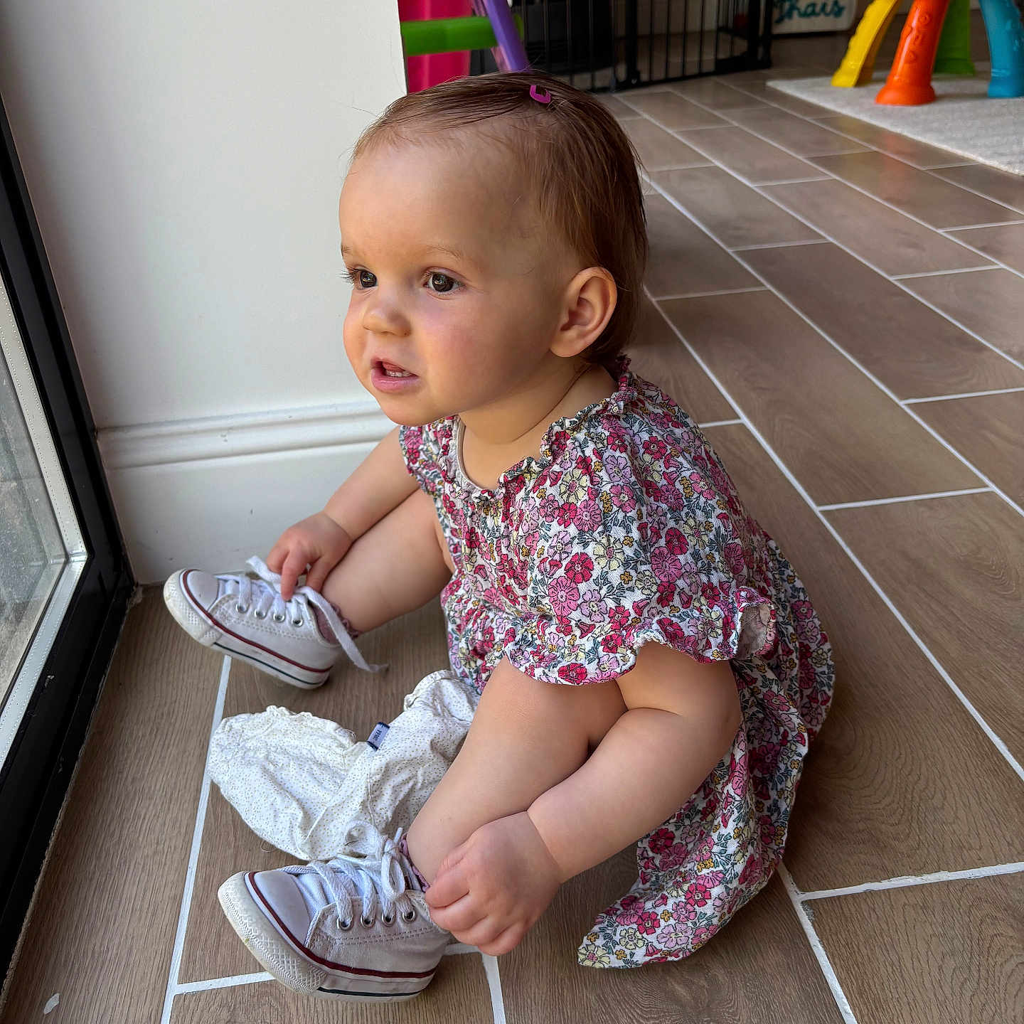 Thaïs a rejoint le concours — aidez-le/la à gagner de superbes lots ! baby, child, converse, curious, dress, floor, footwear, hair_clip, home, indoor, light, natural_light, person, play_area, sitting, sneakers, tile_floor, toddler, toy, window