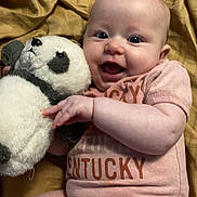 Enora joined the competition — help win amazing prizes! baby, infant, smiling, stuffed_animal, panda, blanket, onesie, clothing, happy, cute, lying_down, child, toy, face, person, skin, hand, furniture, indoors, soft_toy
