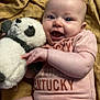 baby, infant, smiling, stuffed_animal, panda, blanket, onesie, clothing, happy, cute, lying_down, child, toy, face, person, skin, hand, furniture, indoors, soft_toy