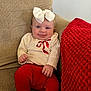 baby, smiling, child, bow, headband, red_pants, cream_top, ribbon, knitted_blanket, chair, beige, textured, happy, cute, indoors, infant, portrait, sitting, cozy, clothing
