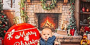 Bella joined the competition — help win amazing prizes! baby, candles, child, christmas, cozy, decorations, festive, fireplace, holiday, indoor, ornament, pants, plaid_shirt, portrait, presents, seasonal, smiling, vest, wood_floor, wreath