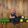 Bella is registered to the contest to win money with this photo: baby, barefoot, child, childhood, cute, denim_overalls, flooring, fun, green_toy, happy, indoor, infant, playful, portrait, sitting, small_toy, smiling, toy_tractor, vehicle_toy, wooden_floor