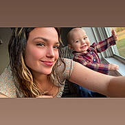 Bella joined the competition — help win amazing prizes! casual_clothing, child, face, family, hair, happy, home, indoor, interaction, natural_light, person, plaid_shirt, portrait, sitting, smiling, toddler, waving, window, woman, young_adult