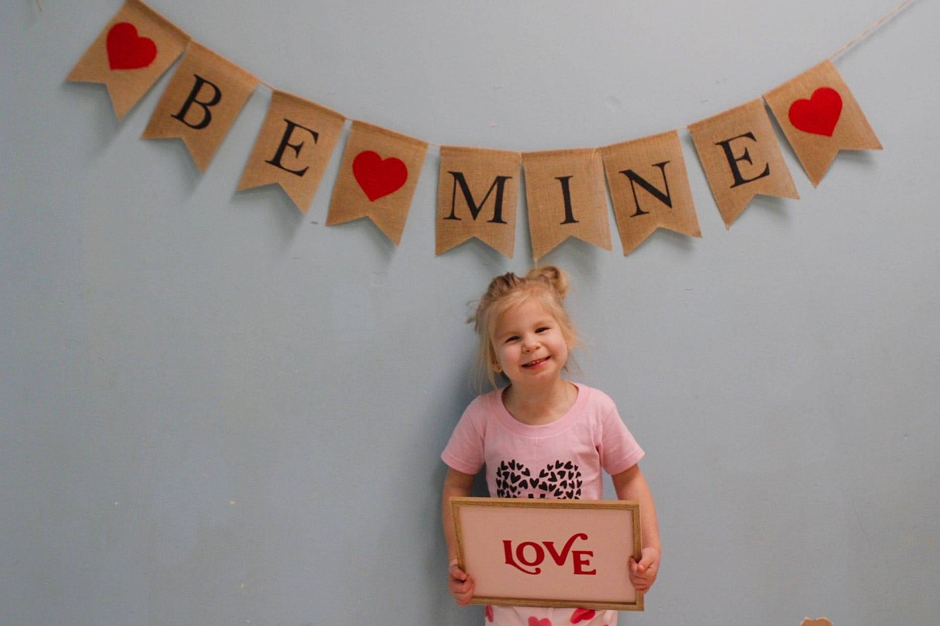 Kennedy is registered to the contest to win money with this photo: advertising, brand, event, font, fun, graphics, handwriting, happy, joy, logo, magenta, pattern, peach, person, room, sleeve, smile, t_shirt, toddler, top