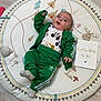 baby, green_tracksuit, adidas, play_mat, flooring, card, smiling, face, child, cactus, moose, tree, mushroom, sock, happy, indoor, person, clothing, celebration, cute