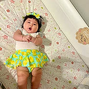 Ellie joined the competition — help win amazing prizes! baby, infant, crib, mattress, lying_down, portrait, face, smiling, open_mouth, bow, hair, dress, skirt, lemon_pattern, colorful_clothing, nursery, patterned_blanket, indoor, crib_rail, cute