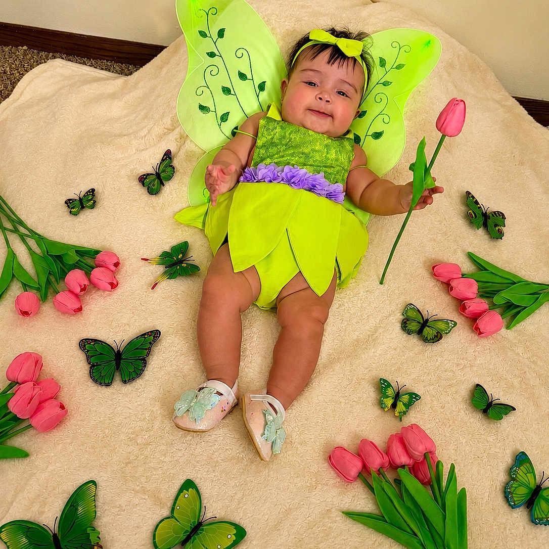 Abbie Grace joined the competition — help win amazing prizes! baby, infant, fairy_costume, green_wings, pink_tulip, flowers, butterflies, blanket, headband, smiling, cute, child, indoors, soft_texture, playful, costume, shoes, green, pink, decorative