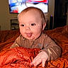 Oliver joined the competition — help win amazing prizes! baby, tongue_out, pajamas, blanket, orange, indoor, child, cute, face, hand, expression, playful, television, blurred_background, home, person, infant, cozy, sleepwear, bed