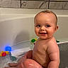 baby, bathtub, bath_toys, child, smiling, water, bathroom, tile, happy, cute, sitting, skin, wet, playful, infant, person, young_child, fun, indoors, childhood