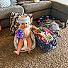Oliver is registered to the contest to win money with this photo: baby, helmet, bumbo_seat, pop_it_toy, toy_bin, carpet, couch, pillow, living_room, child, indoor, playtime, colorful_toys, diaper, blanket, floor, person, seat, home, cute