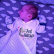 Alfie is registered to the contest to win money with this photo: newborn, baby, sleeping, onesie, mittens, blanket, cloud_pattern, crib, infant, cute, soft_lighting, purple_tint, peaceful, cozy, portrait, indoors, child, face, head, mattress