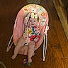 baby, infant, smiling, bow, baby_rocker, wooden_floor, indoor, toy, mop, pet, happy, colorful, clothing, person, child, flooring, home, cute, sitting, playful
