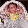 baby, sleeping, blanket, bassinet, yellow_clothing, floral_pattern, cozy, infant, arms_up, soft_texture, peaceful, child, indoors, head, face, cute, resting, comfort, toddler, portrait