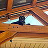 animal, architecture, black_cat, brick_wall, cat, curious, daylight, domestic_animal, feline, light_bulb, looking_down, nature, outdoor, pet, resting, roof, sitting, wood, wooden_beam, yellow_eyes