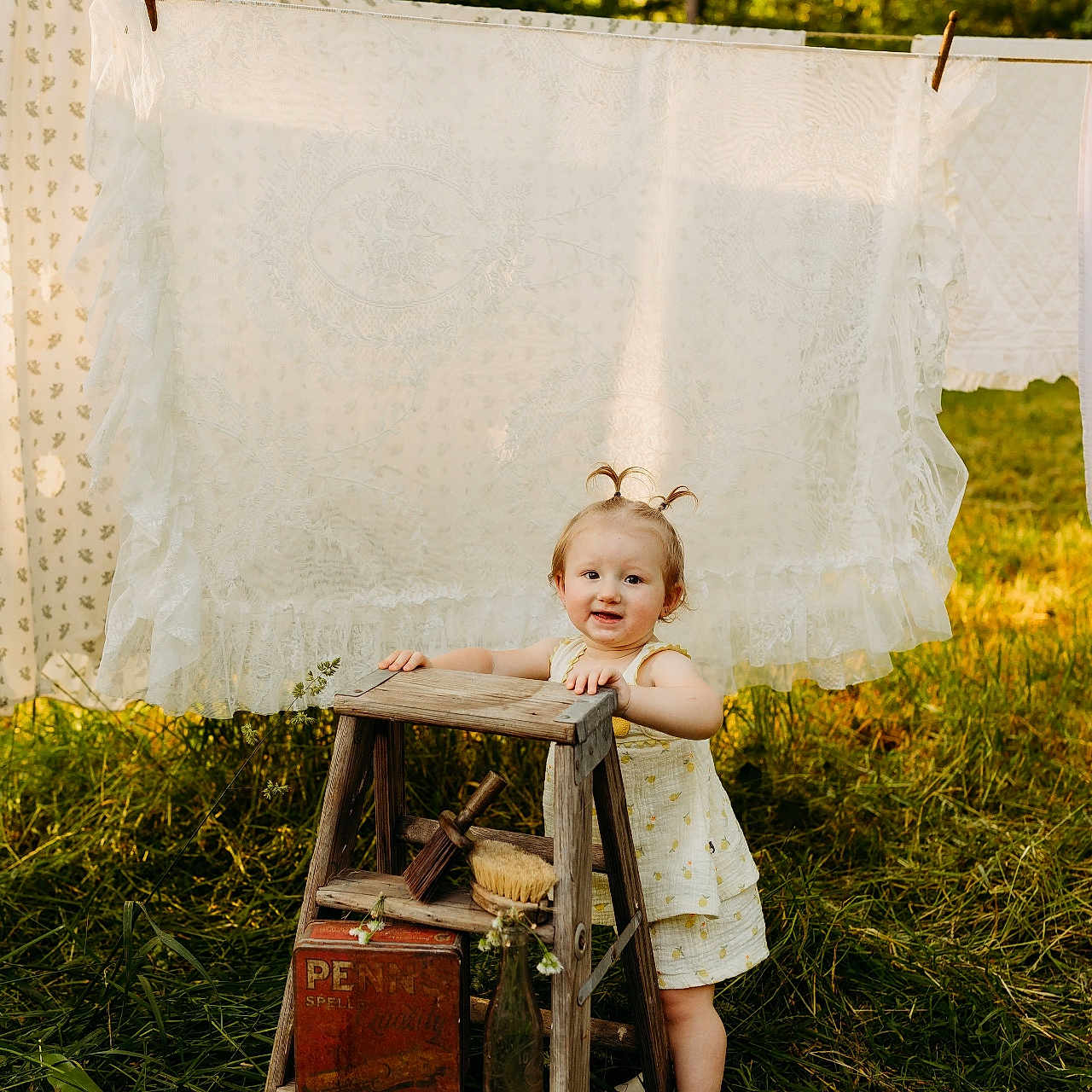 Olivia joined the competition — help win amazing prizes! child, clothesline, daylight, dress, garden, grass, greenery, hair_pigtails, lace, nature, outdoor, playful, sheet, smile, step_ladder, sunlight, toddler, vintage, white_shoes, wood