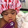 baby, blanket, calm, candid, child, closeup, curly_hair, expression, face, headwear, indoors, person, pink, portrait, shower_cap, skin, sleepy, soft_texture, strawberry_pattern, toddler