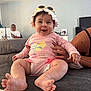 baby, smiling, hat, sunglasses, pink_clothing, diaper, couch, hand, adult, indoor, happy, person, infant, home, furniture, man, desk, computer, relaxed, casual