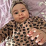 baby, infant, leopard_print, headband, clothing, hand, face, blanket, pattern, purple, cute, portrait, child, lying_down, expression, skin, person, young, indoor, candid
