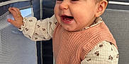 Mira participe au concours pour gagner de l'argent avec cette photo : baby, child, laughing, playpen, indoor, pink_vest, floral_blouse, denim_pants, person, adult, candid, smiling, happy, family, home, cute, face, hand, hair, portrait