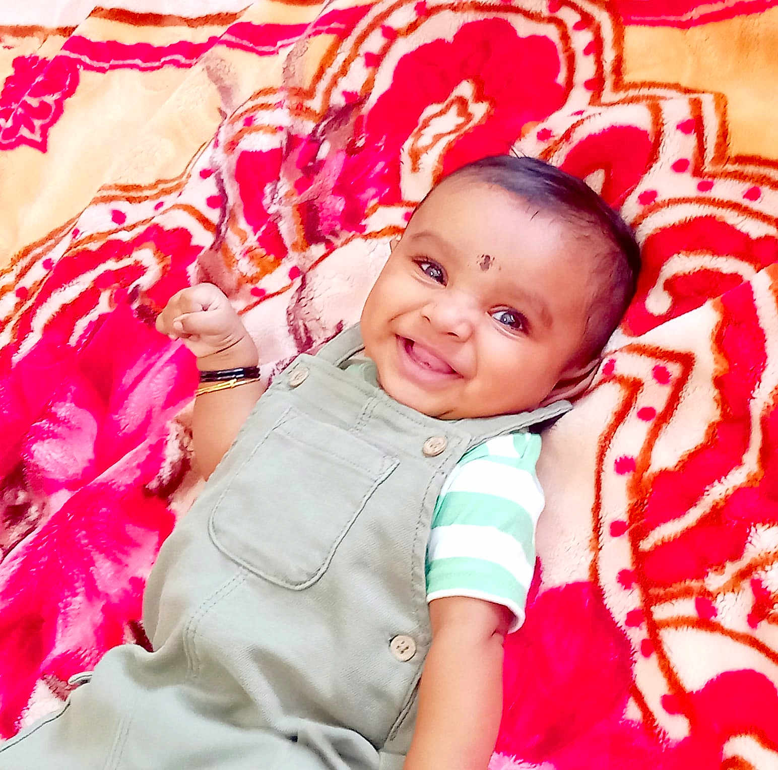 Vishakan joined the competition — help win amazing prizes! baby, smiling, infant, child, overalls, striped_shirt, bracelet, blanket, patterned_blanket, happy, portrait, cute, lying_down, face, skin, clothing, indoor, young_child, bright_colors, expression