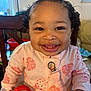 baby, smiling, child, high_chair, pink_bow, curly_hair, onesie, ladybug_pattern, red_cup, indoors, furniture, person, happy, cute, toddler, home, seat, clothing, face, portrait