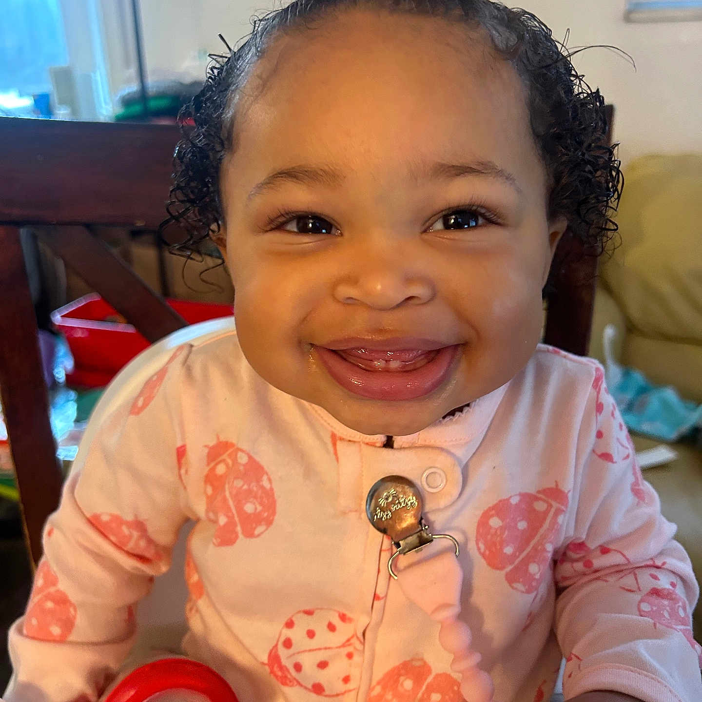 Zennayah joined the competition — help win amazing prizes! baby, child, clothing, curly_hair, cute, face, furniture, happy, high_chair, home, indoors, ladybug_pattern, onesie, person, pink_bow, portrait, red_cup, seat, smiling, toddler