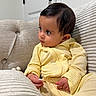 Innie joined the competition — help win amazing prizes! baby, child, yellow_outfit, couch, sofa, indoor, curly_hair, portrait, seated, cute, soft_fabric, texture, hand, face, looking_away, cozy, home, infant, relaxed, casual