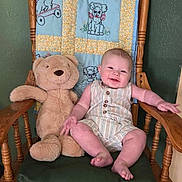 Denver joined the competition — help win amazing prizes! baby, child, toddler, smiling, sitting, teddy_bear, stuffed_animal, wooden_chair, quilt, cushion, indoors, portrait, home, furniture, infant, romper, barefoot, happy, green_wall, photography