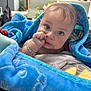 baby, blanket, blue, indoors, person, child, face, hand, jewelry, curious, cozy, soft_texture, comfort, sitting, portrait, young_child, candid, human, skin, expression
