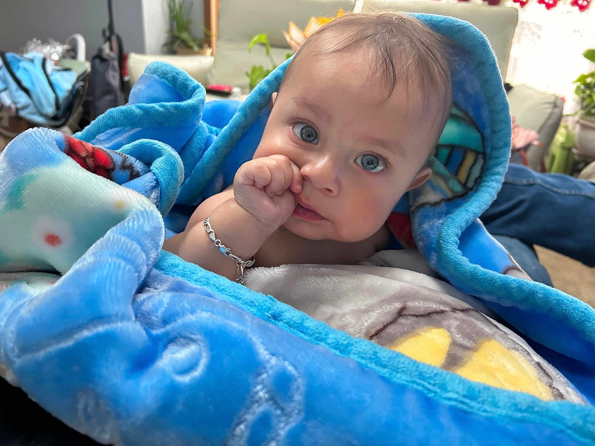 Azarias is registered to the contest to win money with this photo: baby, blanket, blue, indoors, person, child, face, hand, jewelry, curious, cozy, soft_texture, comfort, sitting, portrait, young_child, candid, human, skin, expression