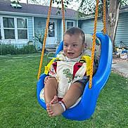 Azarias joined the competition — help win amazing prizes! baby, swing, outdoor, child, grass, blue_swing, yellow_straps, smiling, happy, greenery, house, tree, footwear, playtime, daylight, infant, backyard, seat, person, cute