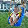 baby, swing, outdoor, child, grass, blue_swing, yellow_straps, smiling, happy, greenery, house, tree, footwear, playtime, daylight, infant, backyard, seat, person, cute
