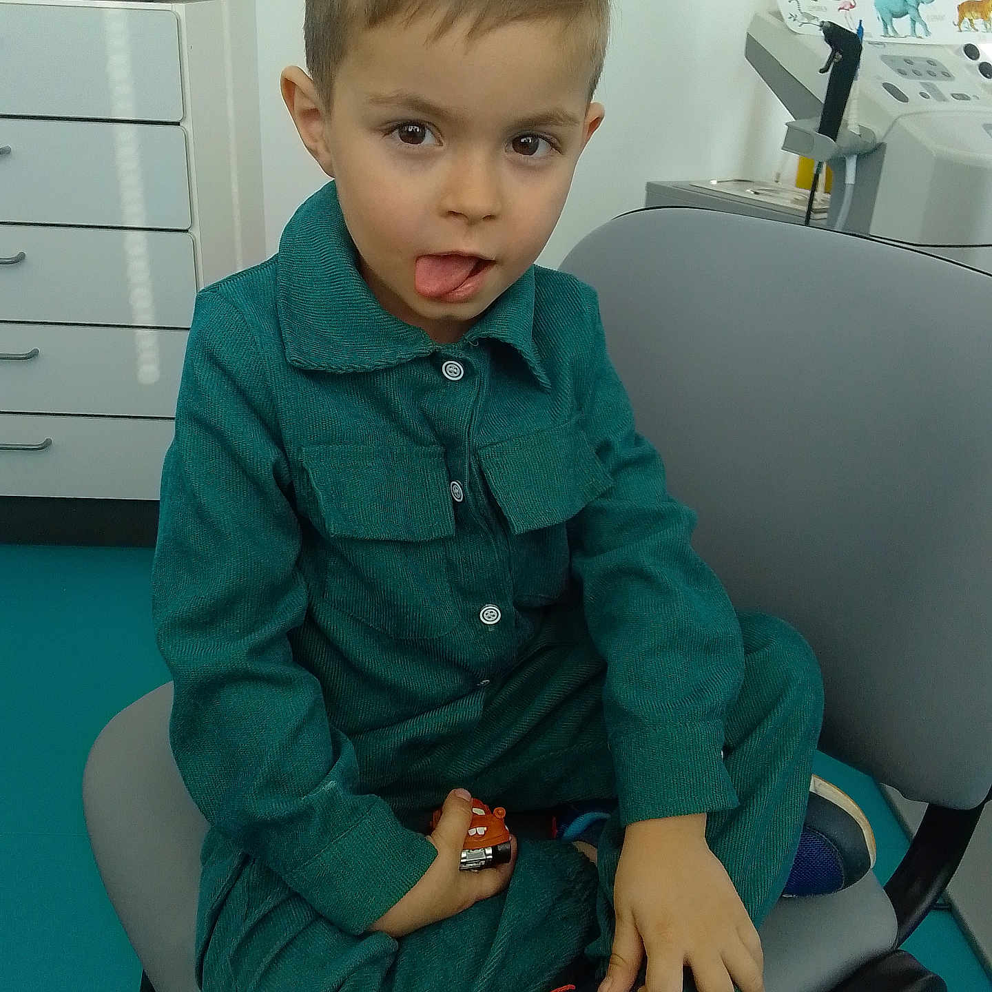Antonio participe au concours pour gagner de l'argent avec cette photo : animal_poster, boy, casual, chair, child, clothing, expression, face, footwear, furniture, hair, indoor, medical_equipment, person, playful, poster, sitting, tongue_out, toy_car, young_child