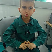 José participe au concours pour gagner de l'argent avec cette photo : child, boy, indoor, sitting, chair, clothing, teal_outfit, pout, hands, window, office, equipment, curly_hair, buttoned_shirt, expression, person, young, portrait, casual, cute