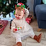 Anna participe au concours pour gagner de l'argent avec cette photo : boots, child, christmas_tree, decoration, dress, floor, gift, happy, headband, holiday, indoors, novelty_glasses, ornament, playful, presents, sitting, smile, sofa, toddler, tree_skirt