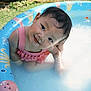 baby, child, cute, face, garden, grass, head, inflatable_pool, outdoor, pink, playful, pool, sitting, smiling, summer, sunny, swimsuit, toddler, water, wet_hair