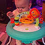 baby, child, indoor, walker, toy, lion_toy, carpet, colorful, playtime, footwear, person, floor, lighting, furniture, activity, cute, infant, exploring, room, play