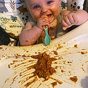 Arthur joined the competition — help win amazing prizes! baby, messy, food, high_chair, spoon, happy, smiling, child, feeding, face, arm, clothing, table, sauce, seat, indoor, cute, playful, fun, eating