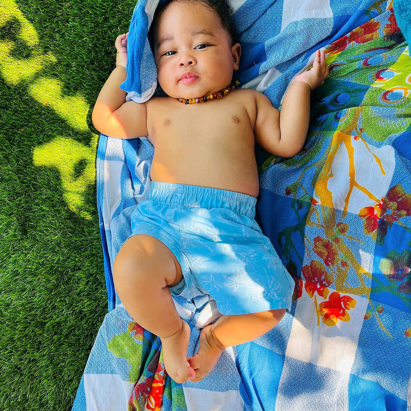 Djewen a rejoint le concours — aidez-le/la à gagner de superbes lots ! baby, bare_chest, blanket, blue_shorts, child, colorful, cute, grass, greenery, infant, lying_down, nature, necklace, outdoor, patterned_blanket, peaceful, relaxing, skin, summer, sunlight
