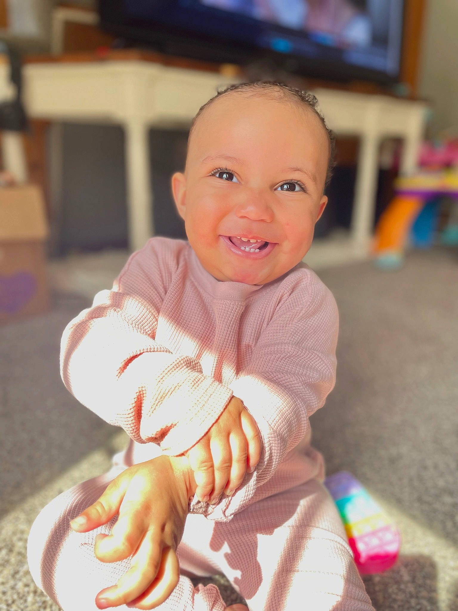 Alana joined the competition — help win amazing prizes! baby, baby_toddler_clothing, cheek, child, flooring, fun, happy, joy, led_backlit_lcd_display, membranophone, person, room, sitting, skin, sleeve, smile, television, thumb, toddler, wheel