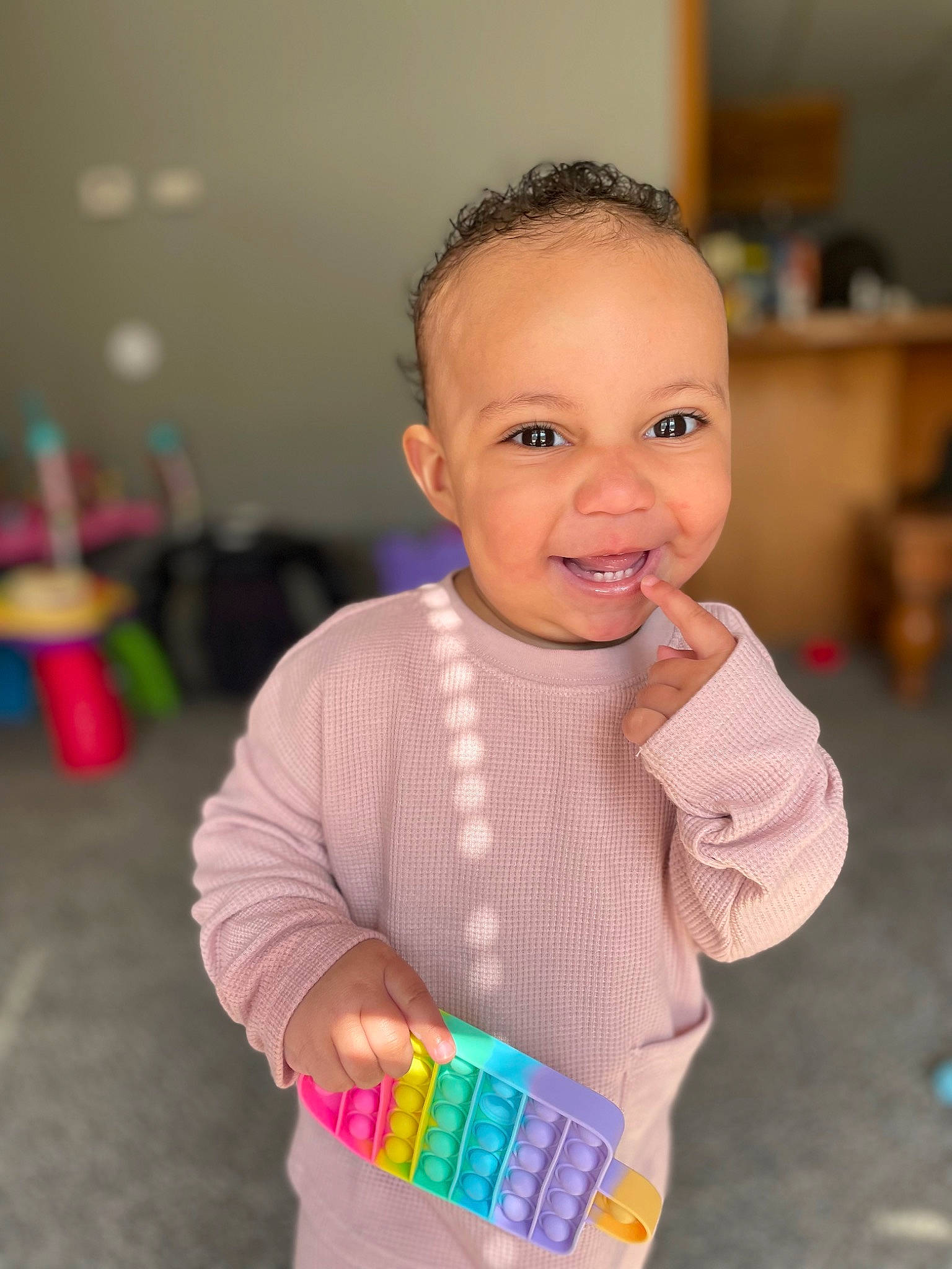 Alana is registered to the contest to win money with this photo: arm, baby, baby_playing_with_toys, baby_toddler_clothing, cheek, child, face, facial_expression, finger, fun, hairstyle, happy, head, joy, organ, person, skin, sleeve, smile, standing