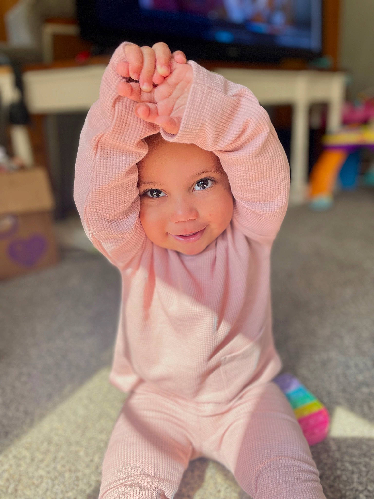 Alana is registered to the contest to win money with this photo: baby, baby_toddler_clothing, cap, cheek, child, finger, floor, flooring, fun, gesture, happy, headgear, headwear, nose, person, pink, purple, skin, sleeve, smile
