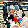 aisle, baby, blanket, bottles, car_seat, child, colorful, cute, grocery_store, hat, indoor, minnie_mouse, person, plush_toy, retail, shelf, shopping, shopping_cart, soft, sports_drink